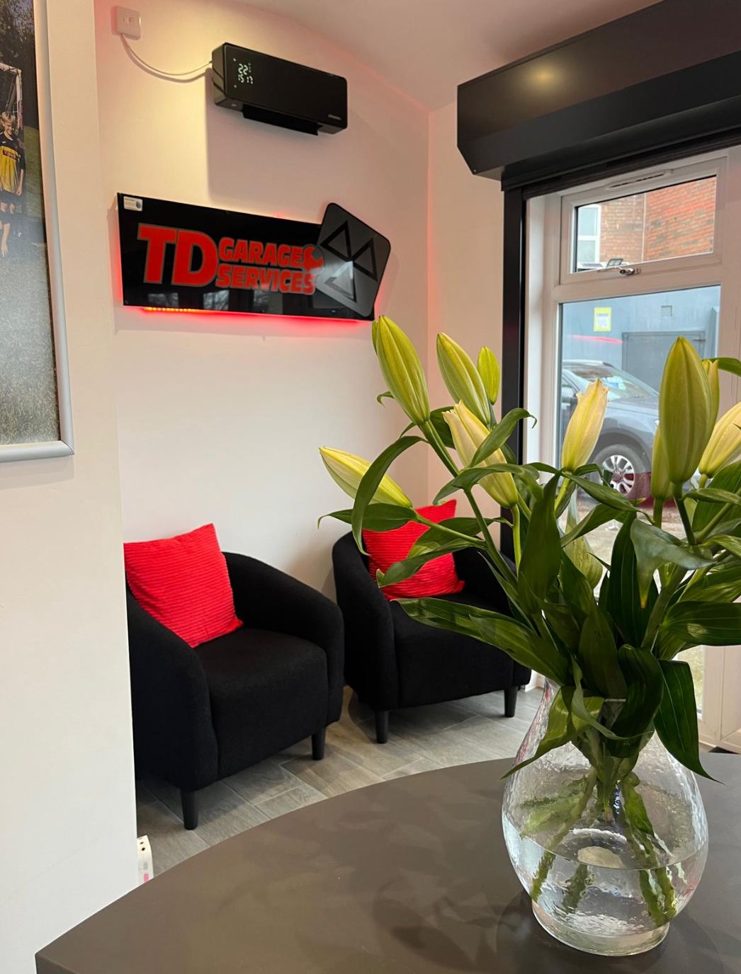 Reception: black armchairs with red cushions, fresh lilies on the table and the TD sign